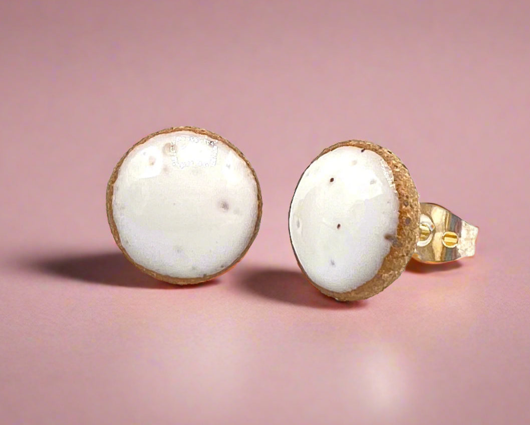 Pair of round earrings with white centers and gold bases on a white background