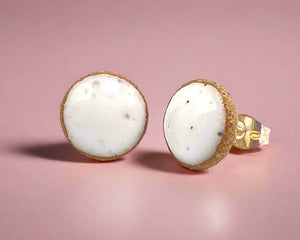 Pair of round earrings with white centers and gold bases on a white background