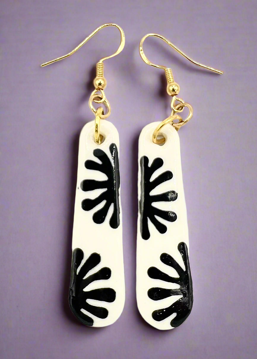Pair of earrings with black leaf-like patterns on a white background