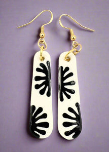 Pair of earrings with black leaf-like patterns on a white background