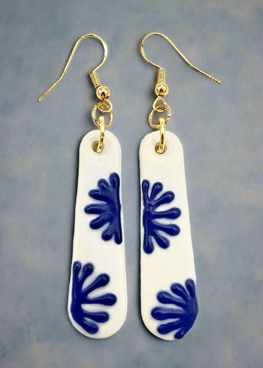 Pair of earrings with blue starburst designs on a white background